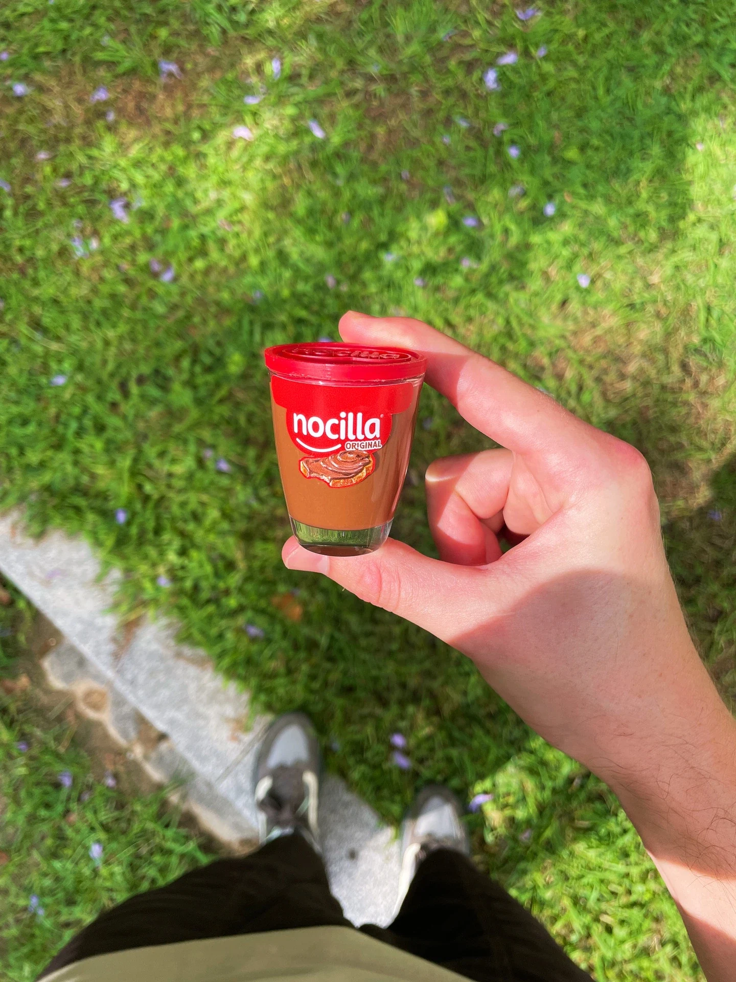 Una mano sostiene el chupito con forma de bote de Nocilla
