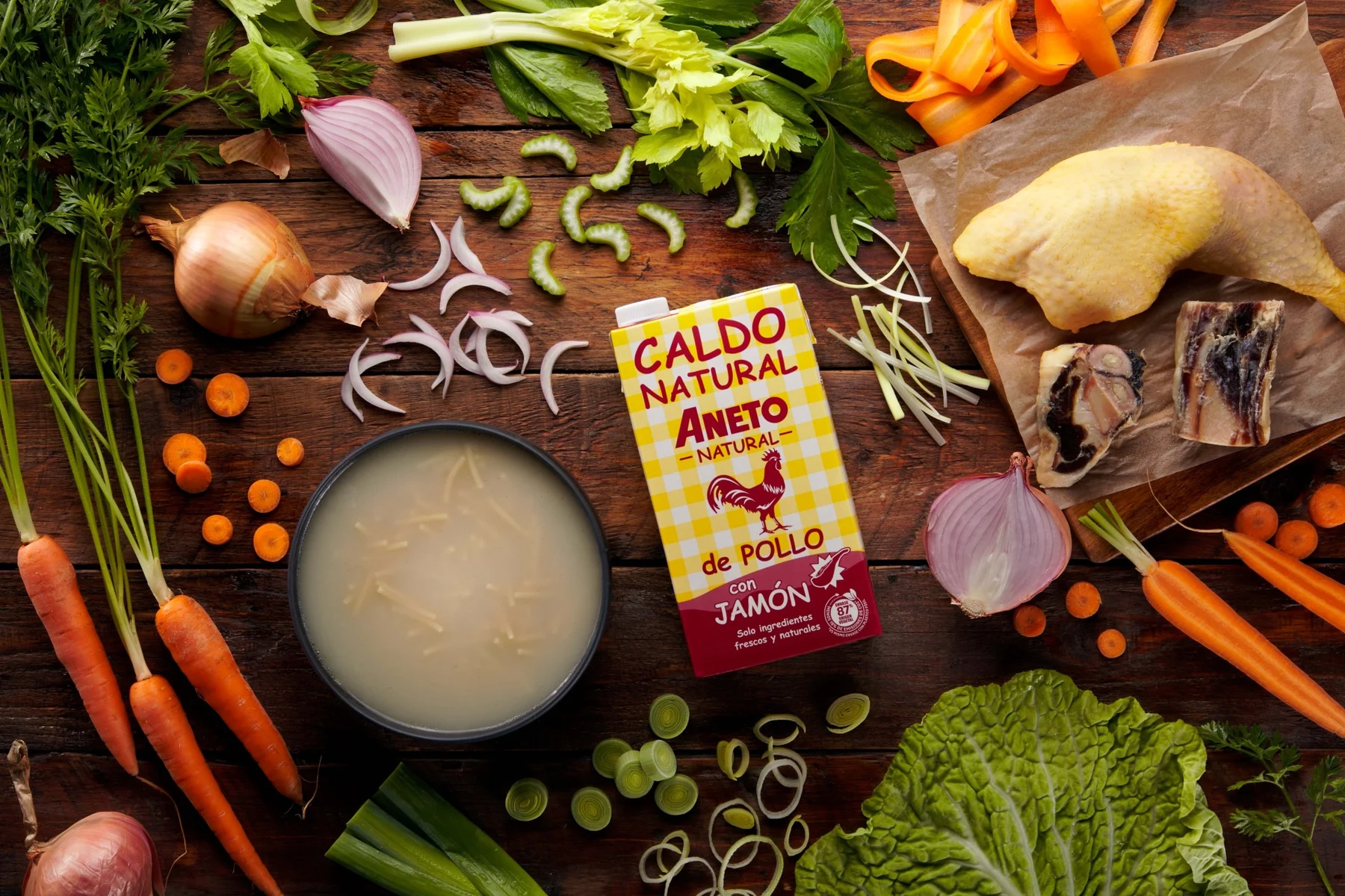 Caldo Aneto de pollo con jamón rodeado de ingredientes frescos