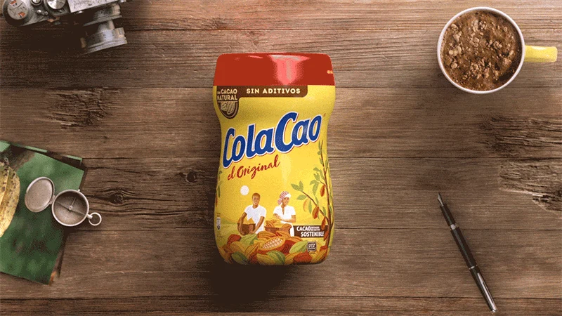 Un bote de ColaCao Original y una taza sobre una mesa de madera