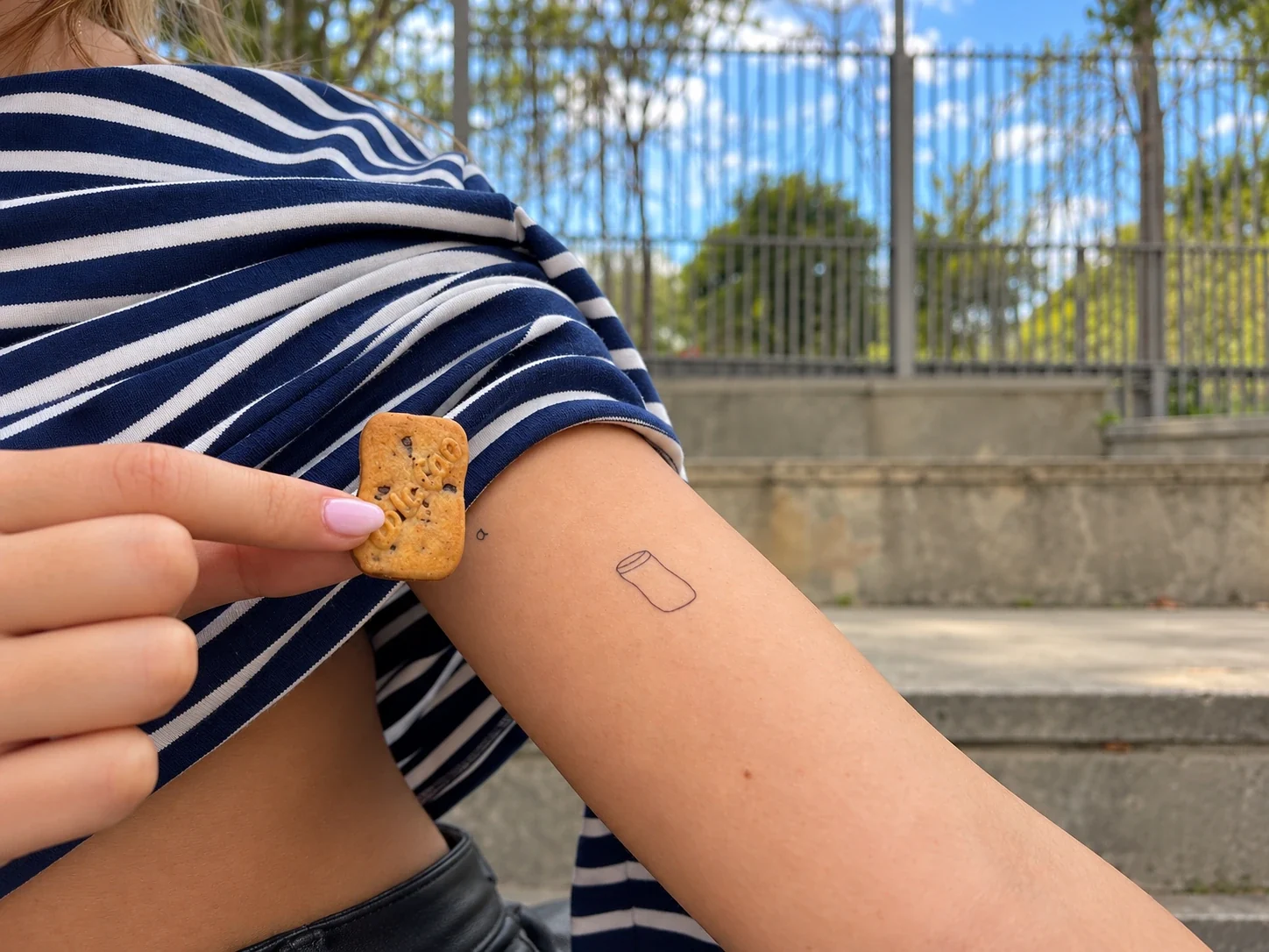 Una galleta de ColaCao junto a un tatuaje de su bote en un brazo