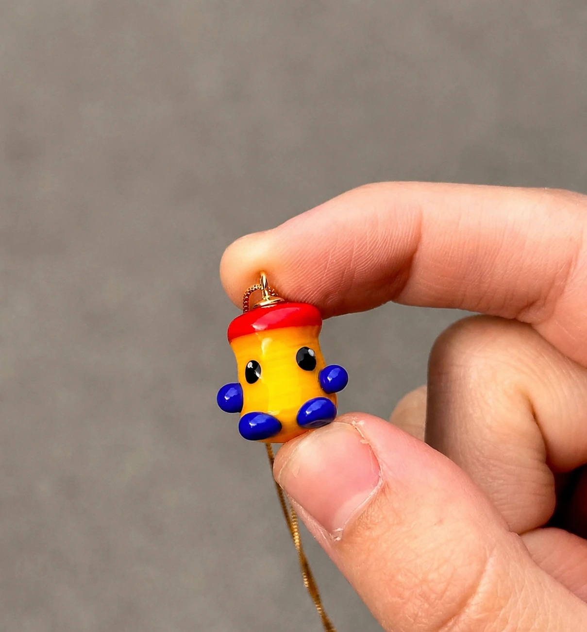 Una mano sostiene la joya de un pequeño bote de ColaCao con ojos